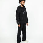 Head to toe angled side profile of the WOA Knit Hoodie in Black.The Knit Hoodie is paired with the Knit Sweatpants in black.