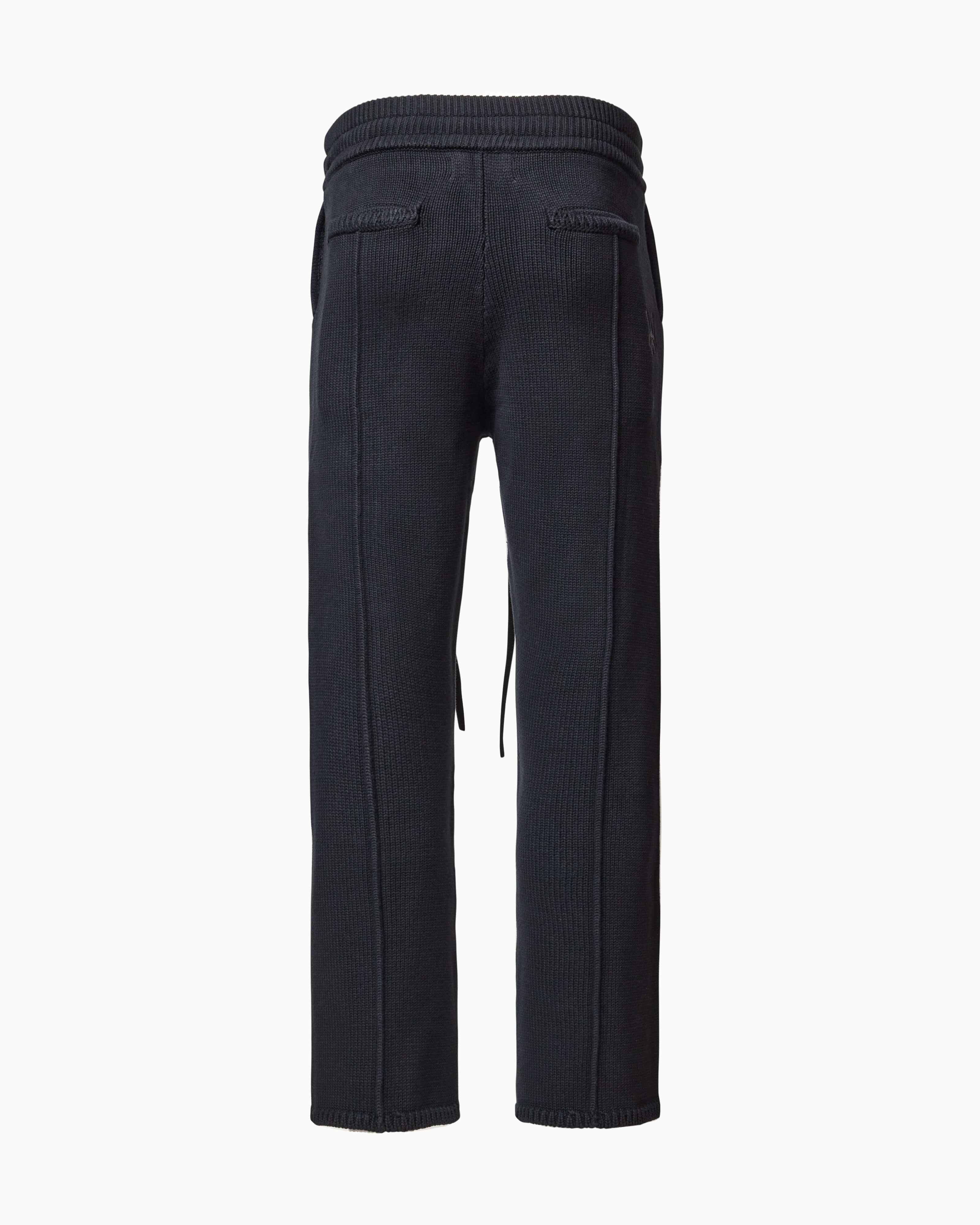 Back of Wisdom of Age Knit Sweatpants in Black. Back welt pockets and WA logo chain stitched below back right pocket on the side.