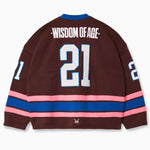 Rear view of the Wisdom Of Age Knit Hockey Jersey with the number 21 in white with a blue outline on the center, Wisdom of age on the name plate. Pink Stripe followed by a blue stripe followed by a pink stripe.