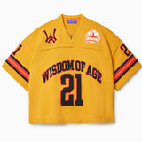 Front view of Wisdom Of Age Knit Football Jersey in Mustard Short Sleeve. Wisdom Of Age written on the chest in black with a red outline with the number 21 under. WA Logo on the right chest, Skyline patch on the left chest. 